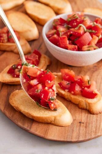 Bruschetta assembled with tomato topping spooned onto toasted bread.