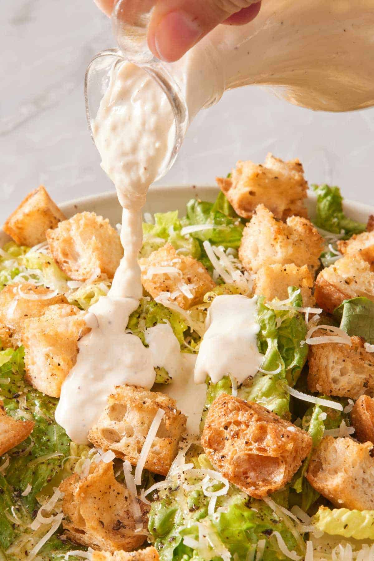 Caesar salad dressing drizzled over a salad.