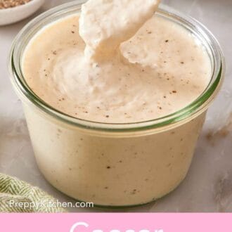 Pin image showing a spoon dipped into a jar of Caesar salad dressing.