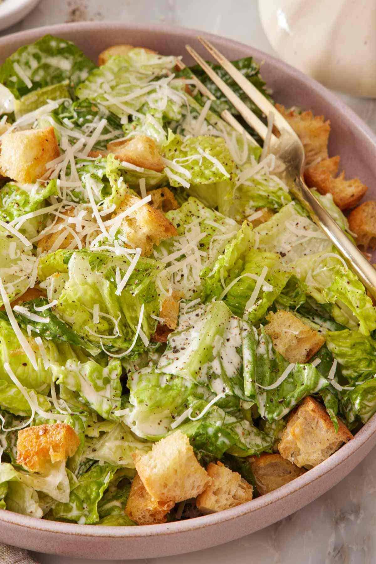 Close-up of a plate of Caesar salad with a fork.