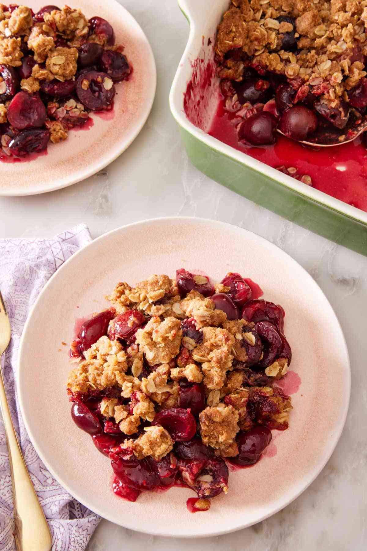 Overhead shot of fresh cherry crisp on a white plate with another serving in the background.