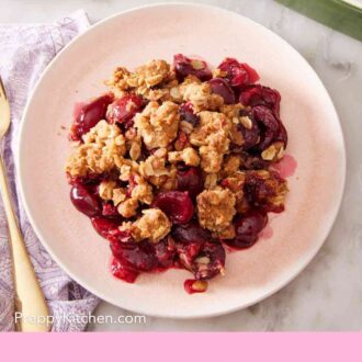 Pinterest graphic showing an overhead shot of cherry crisp on a white plate.