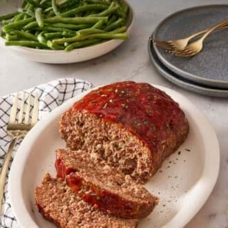 Pinterest graphic showing sliced meatloaf on a serving dish with green beans in the background.