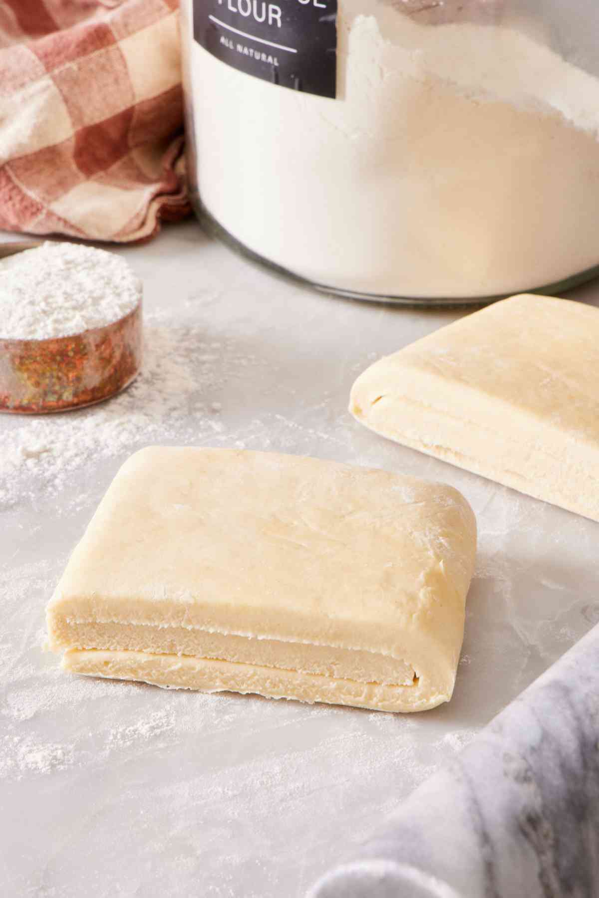 Puff pastry tri-folded like a letter into a square shape, with another square next to it.