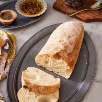 Pinterest graphic showing homemade ciabatta sliced with condiments in the background.