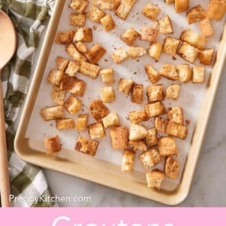 Pinterest graphic showing an overhead shot of homemade croutons on a lined baking sheet.