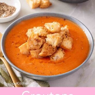 Pinterest graphic showing a bowl of tomato soup topped with crunchy croutons.