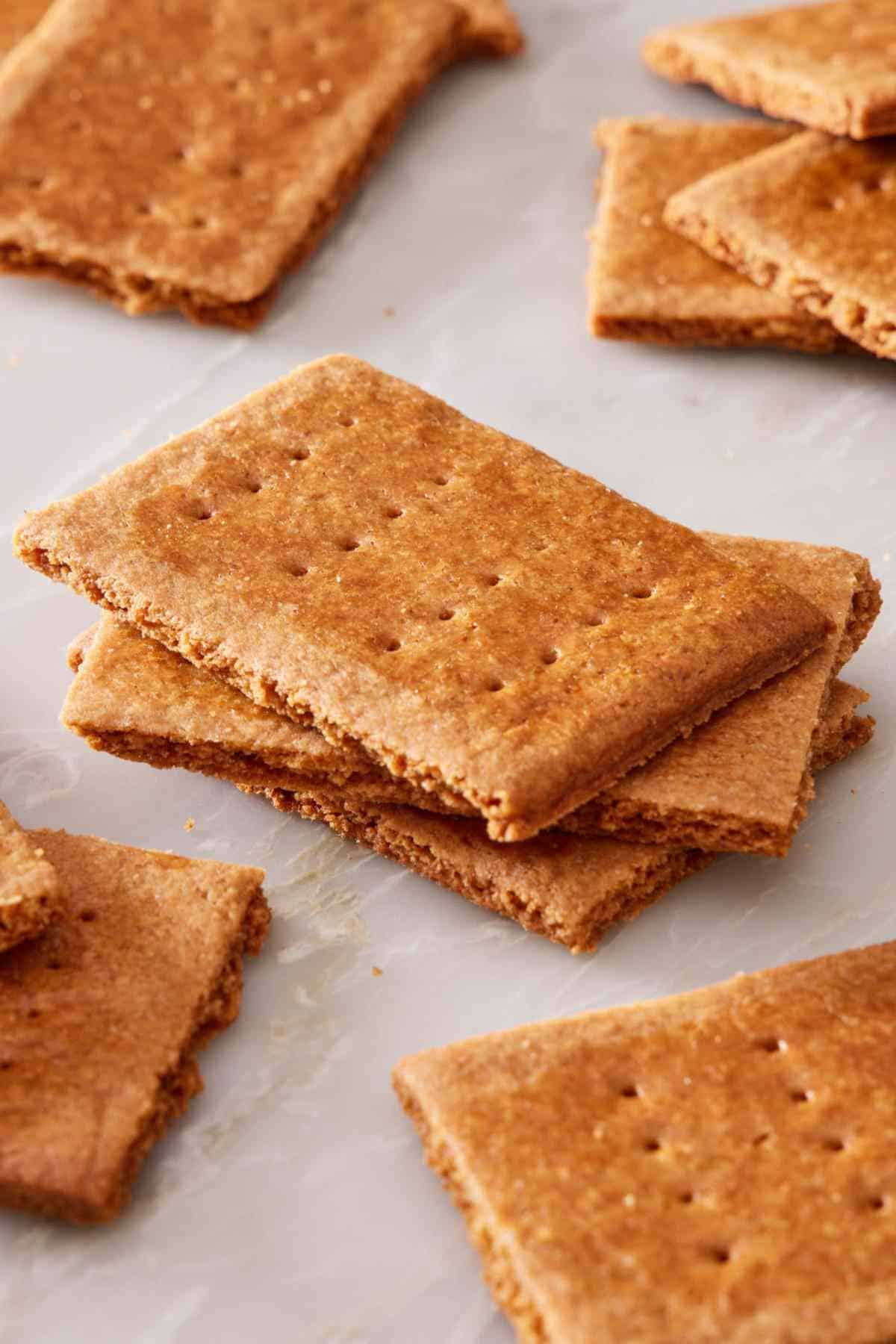 Close up of a stack of homemade graham crackers with more crackers all around it.