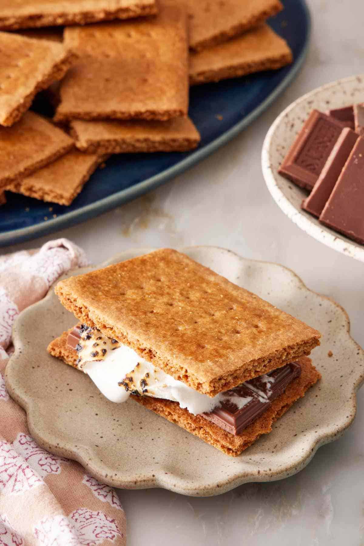 S'more made with homemade graham crackers. More crackers and chocolate in the background.
