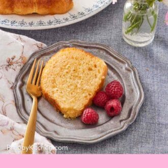 Pinterest graphic showing an overhead shot of a slice of rum baba Bundt cake with raspberries on the side.