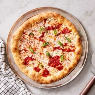Overhead shot of a pizza with a pizza cutter and table linen on the side.