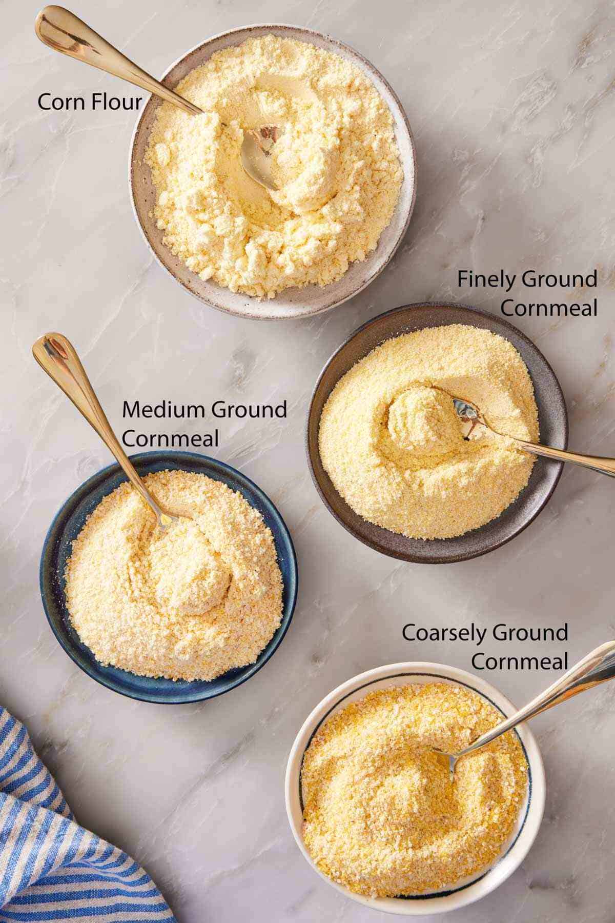 Overhead image showing different types of cornmeal in bowls with spoons.