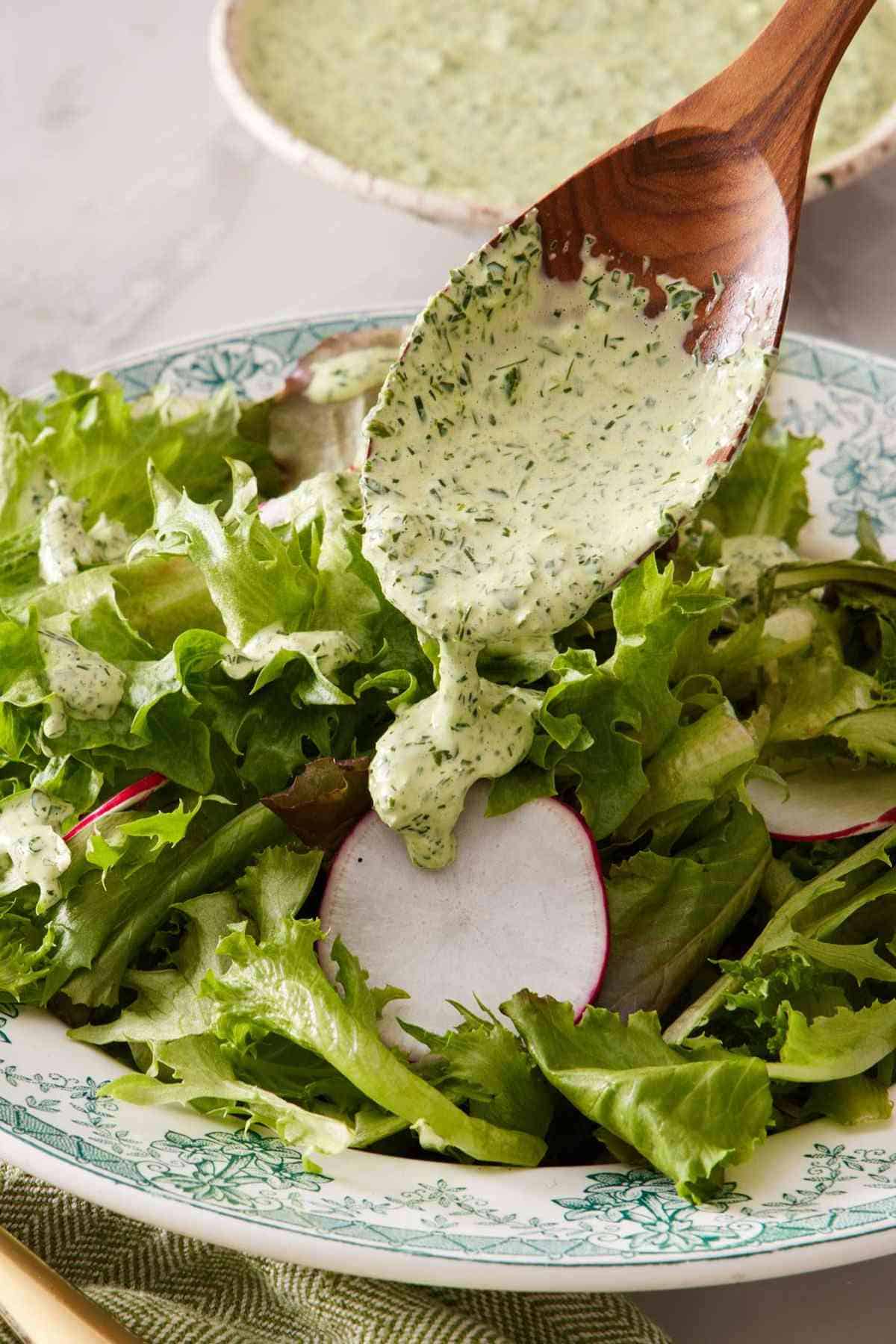 Homemade green goddess dressing spooned over salad greens.