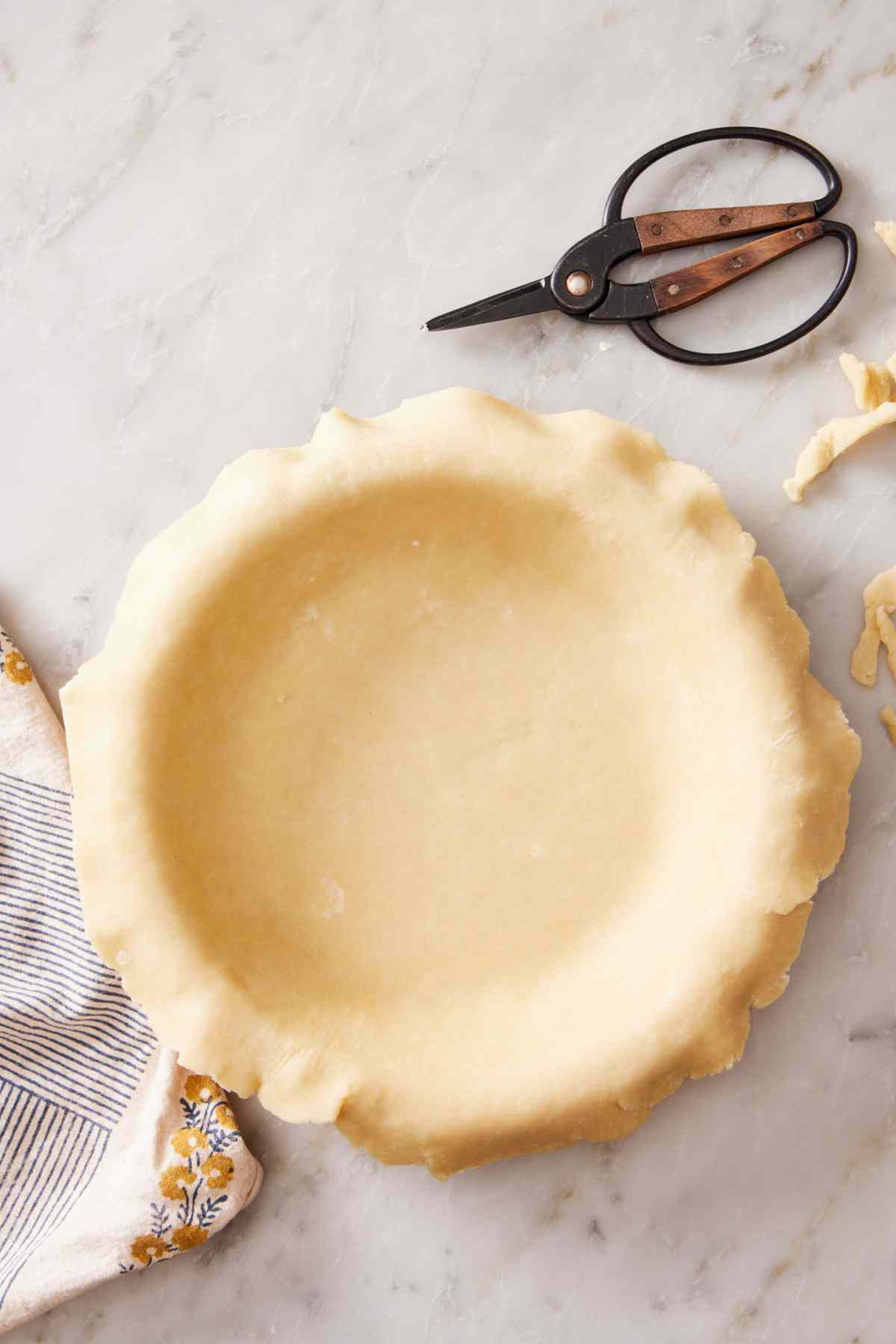 Homemade pie dough placed over a pie dish.