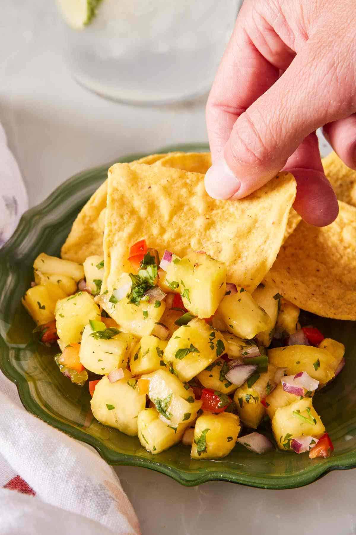 Easy pineapple salsa scooped with a tortilla chip.