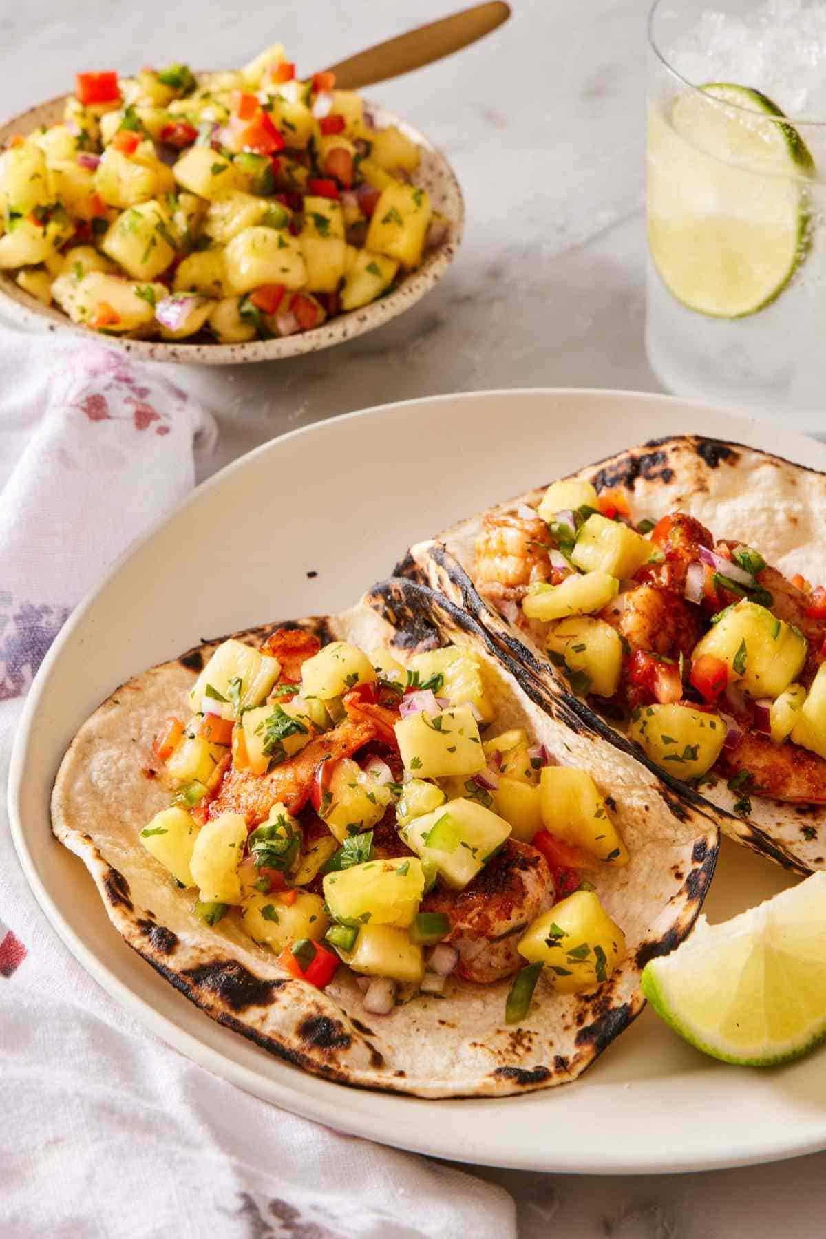 Two charred tortillas topped with pineapple salsa on a plate.