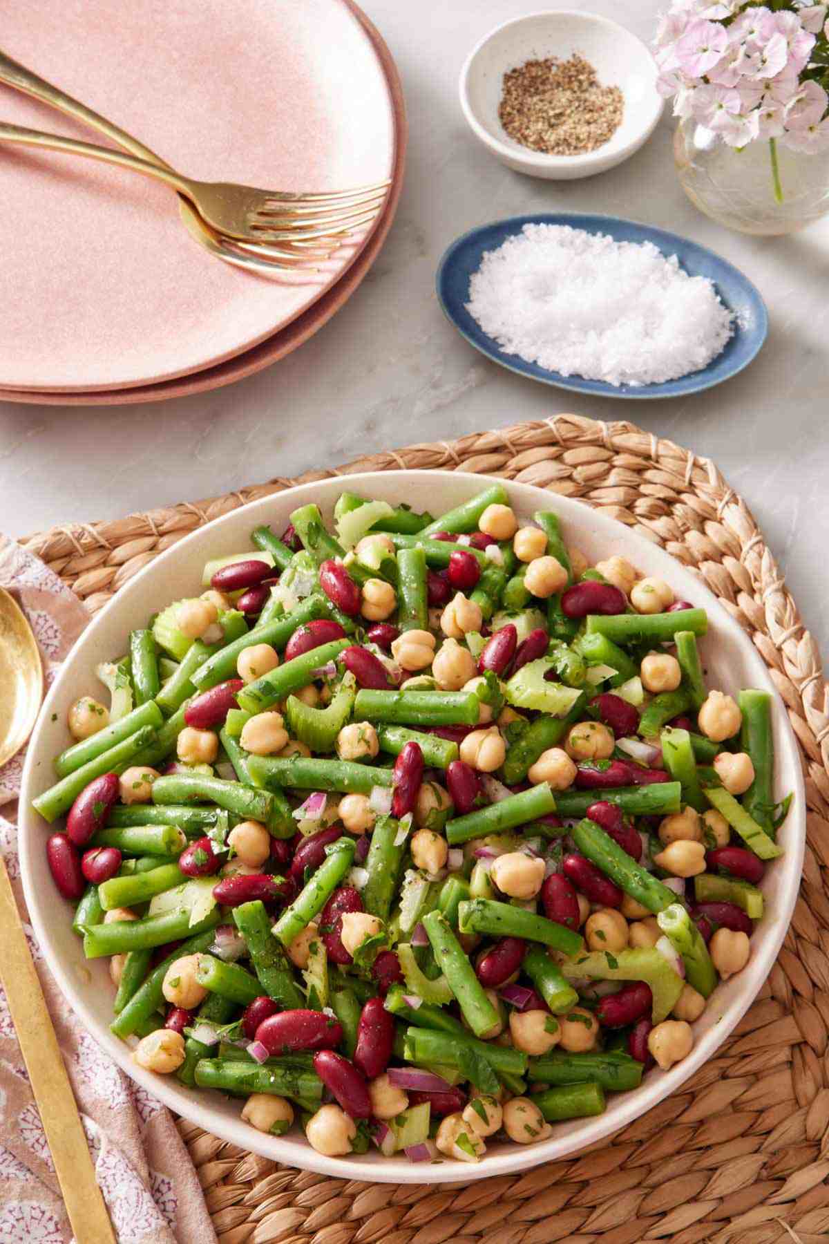 Classic three bean salad in a large bowl with salt and pepper in the background.