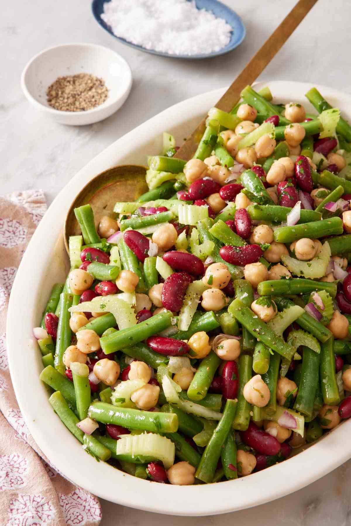 Three bean salad in a platter with a serving spoon.