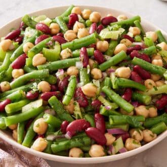 Three bean salad in a bowl with a serving spoon alongside.