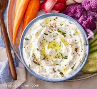 Pinterest graphic showing an overhead shot of tzatziki in a bowl on a platter with colorful veggies.