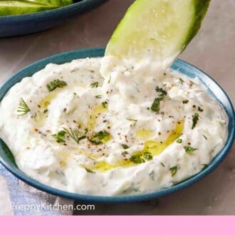Pinterest graphic showing a slice of cucumber dipped into tzatziki.