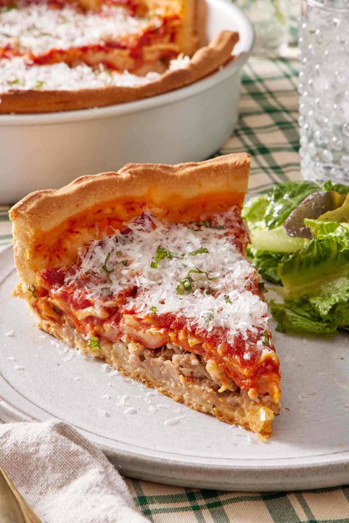 A slice of deep dish pizza with a side salad on a plate.