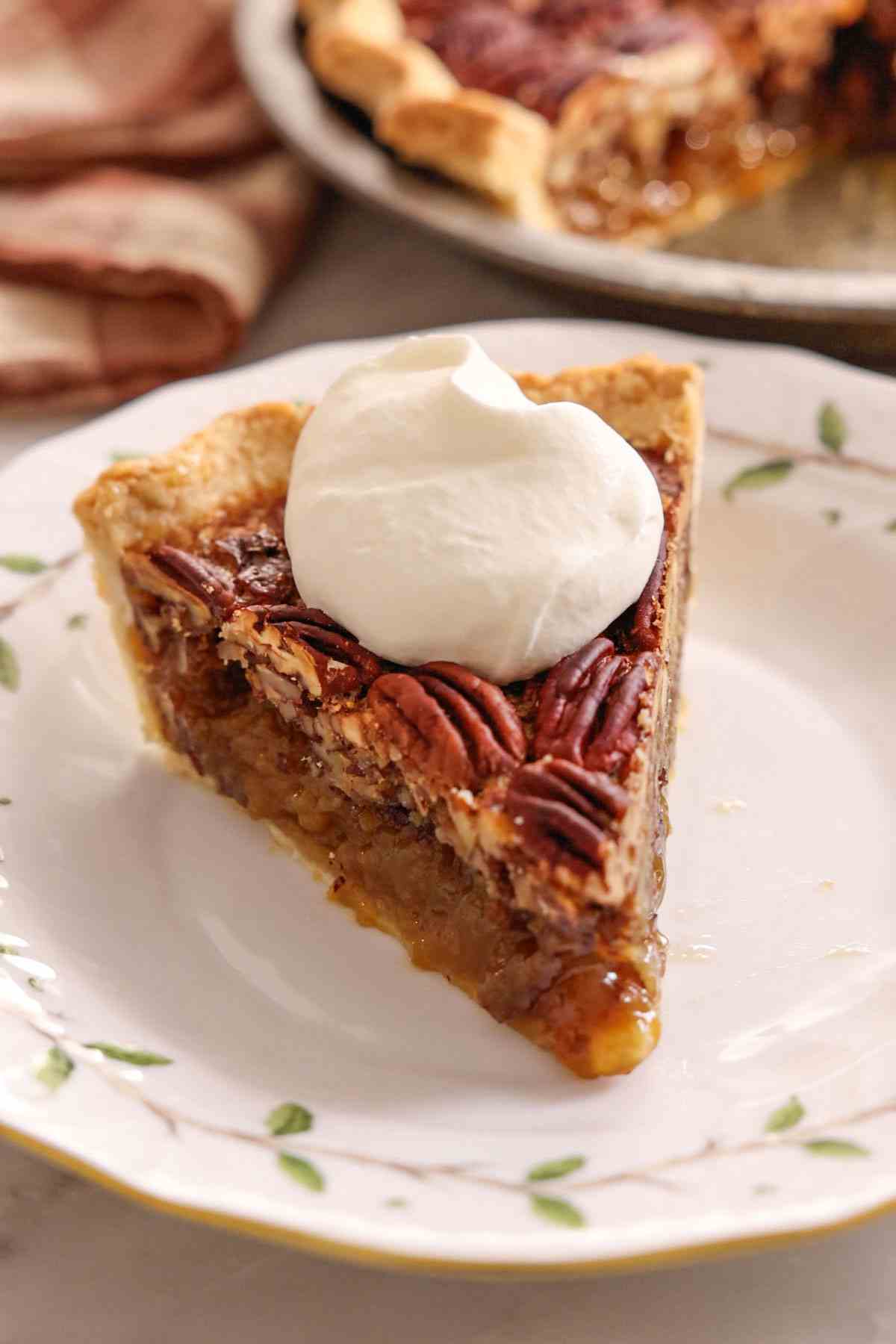A slice of pecan pie topped with whipped cream.