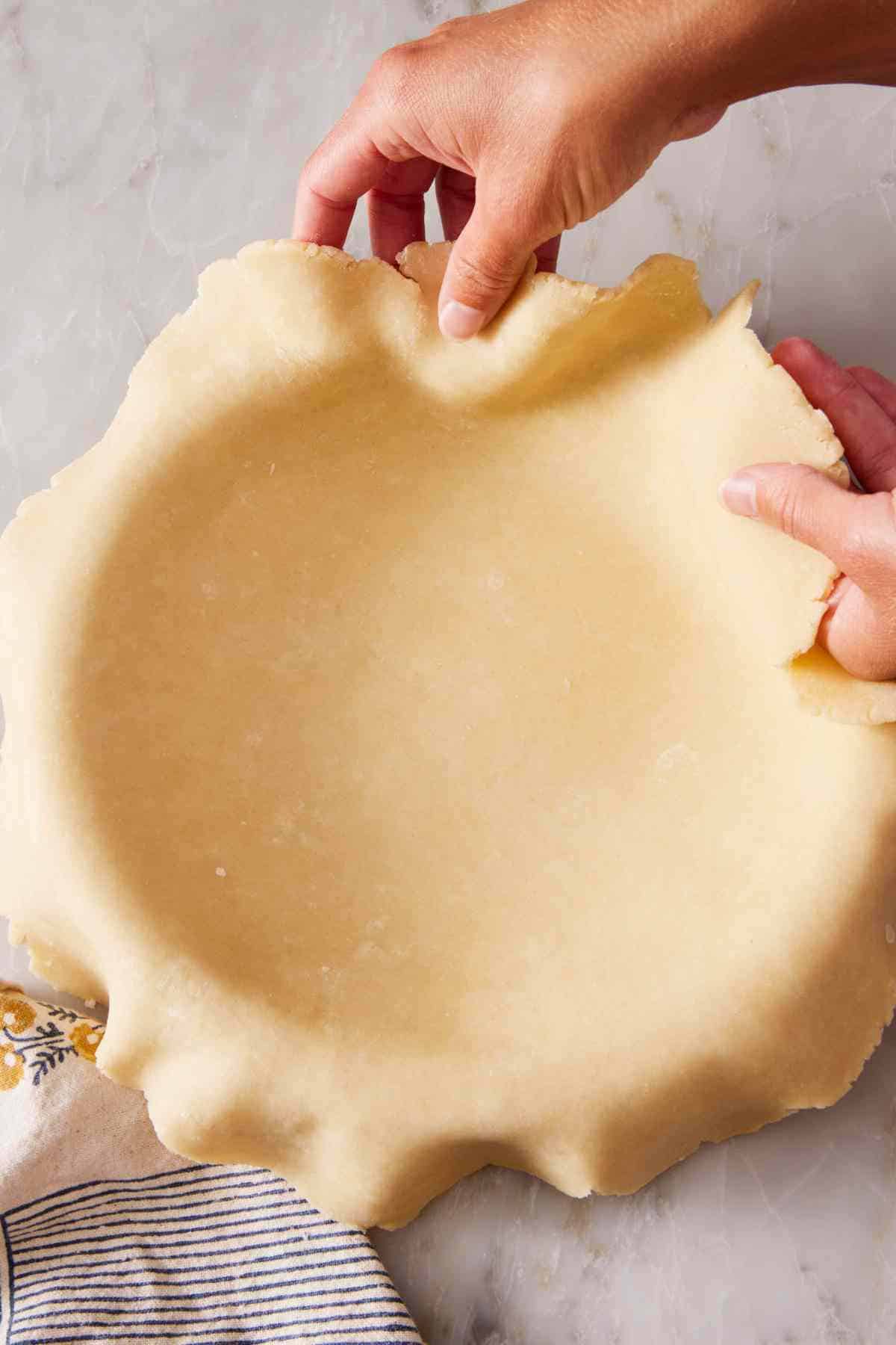 Rolled pie dough placed in a pie dish.