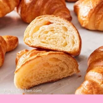 Pinterest graphic showing a halved croissant on a counter with other whole flaky croissants.