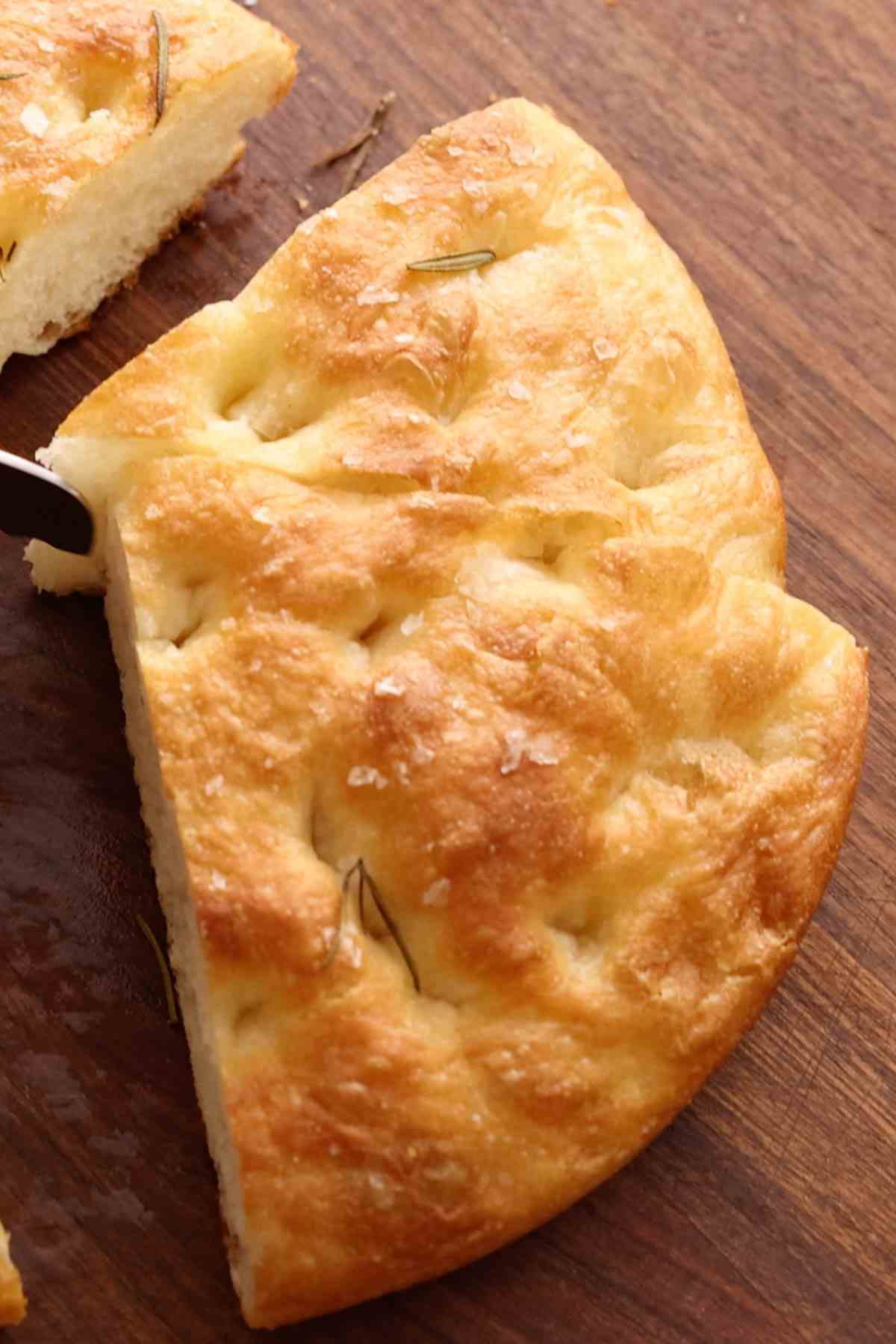 Close-up of round focaccia cut into triangles.