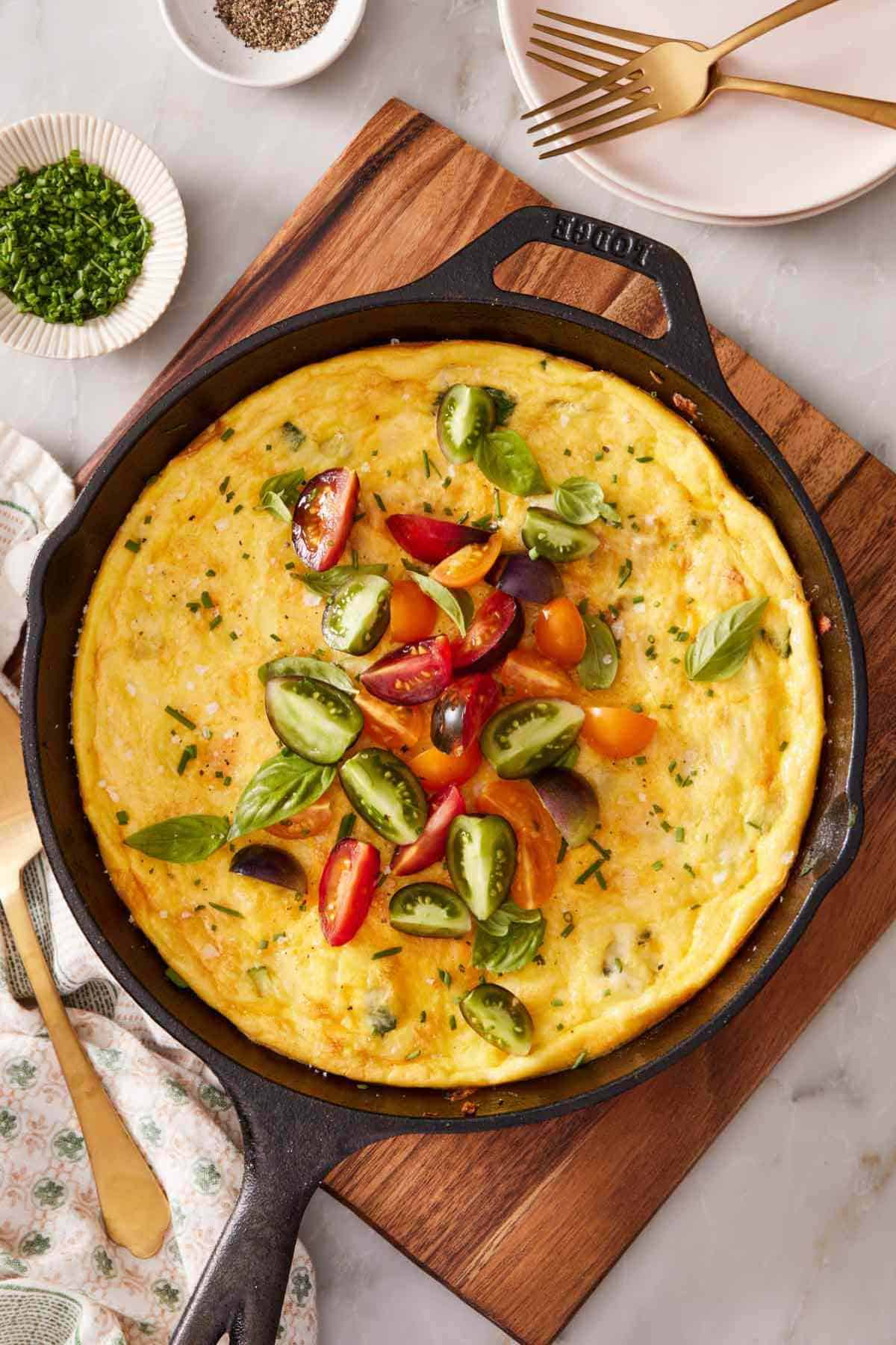 Overhead shot of a homemade frittata with sliced cherry tomatoes sprinkled on top.