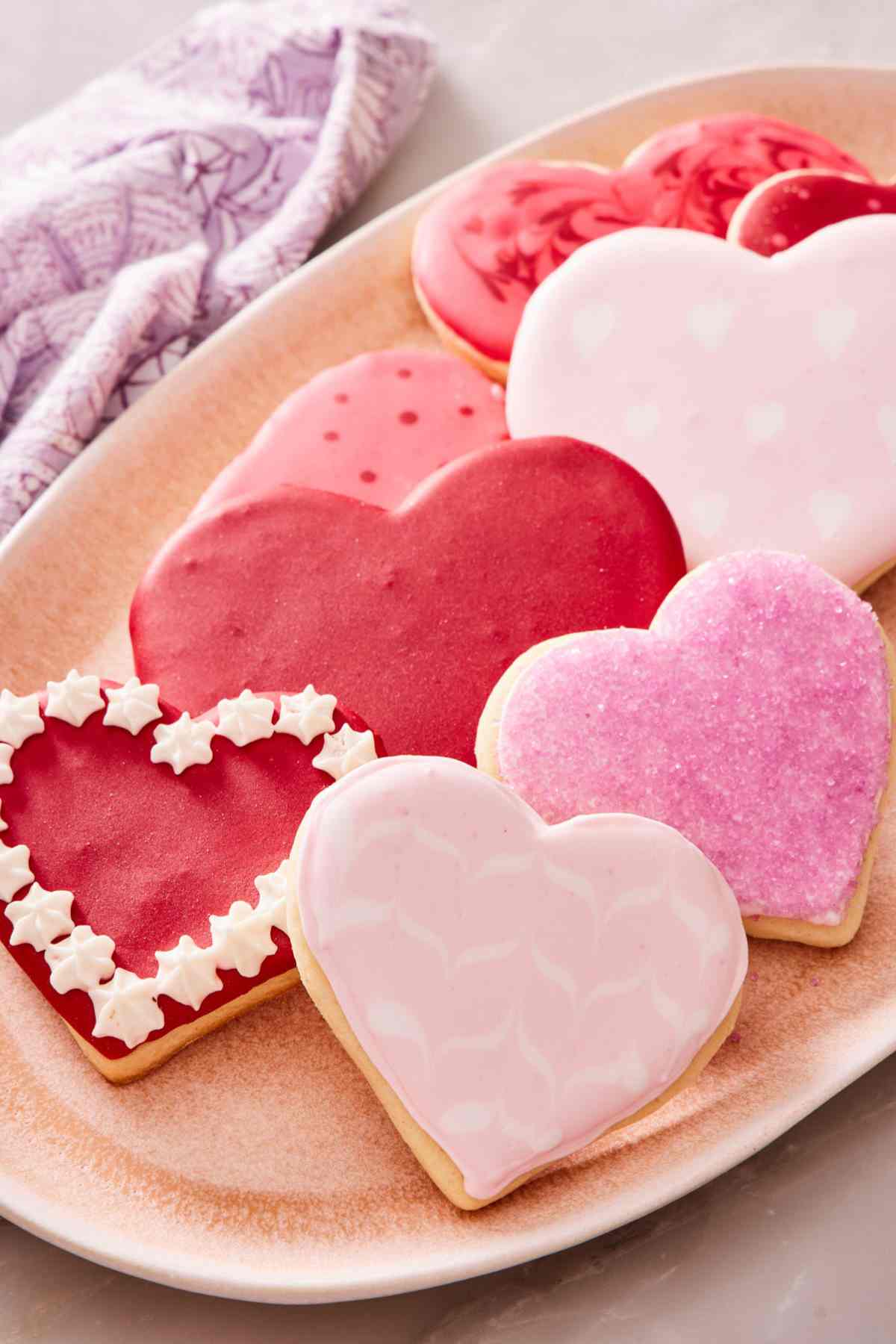 Heart-shaped sugar cookie recipe decorated with different colors and patterns for Valentine's Day.