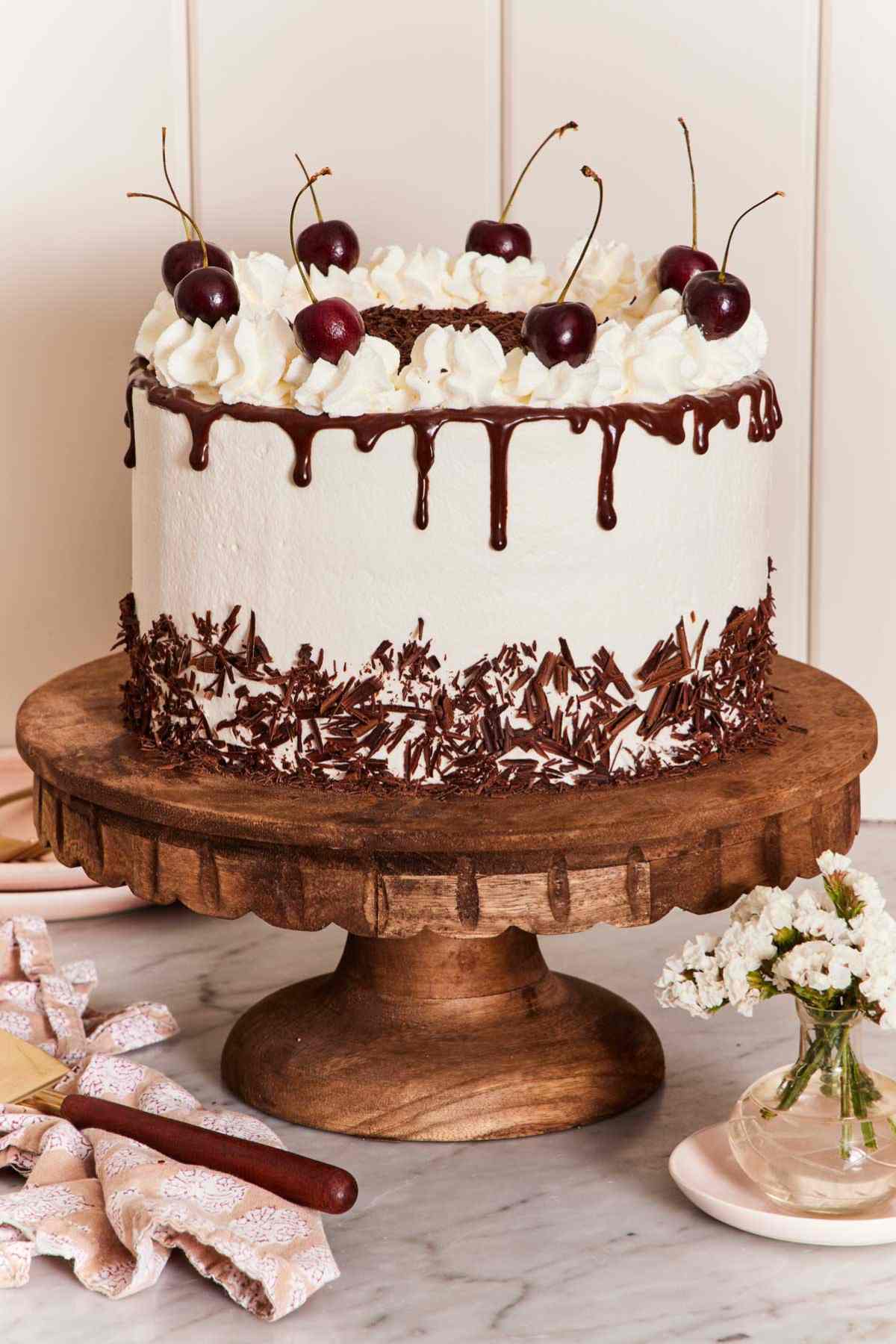 A black forest cake on a wooden cake stand.