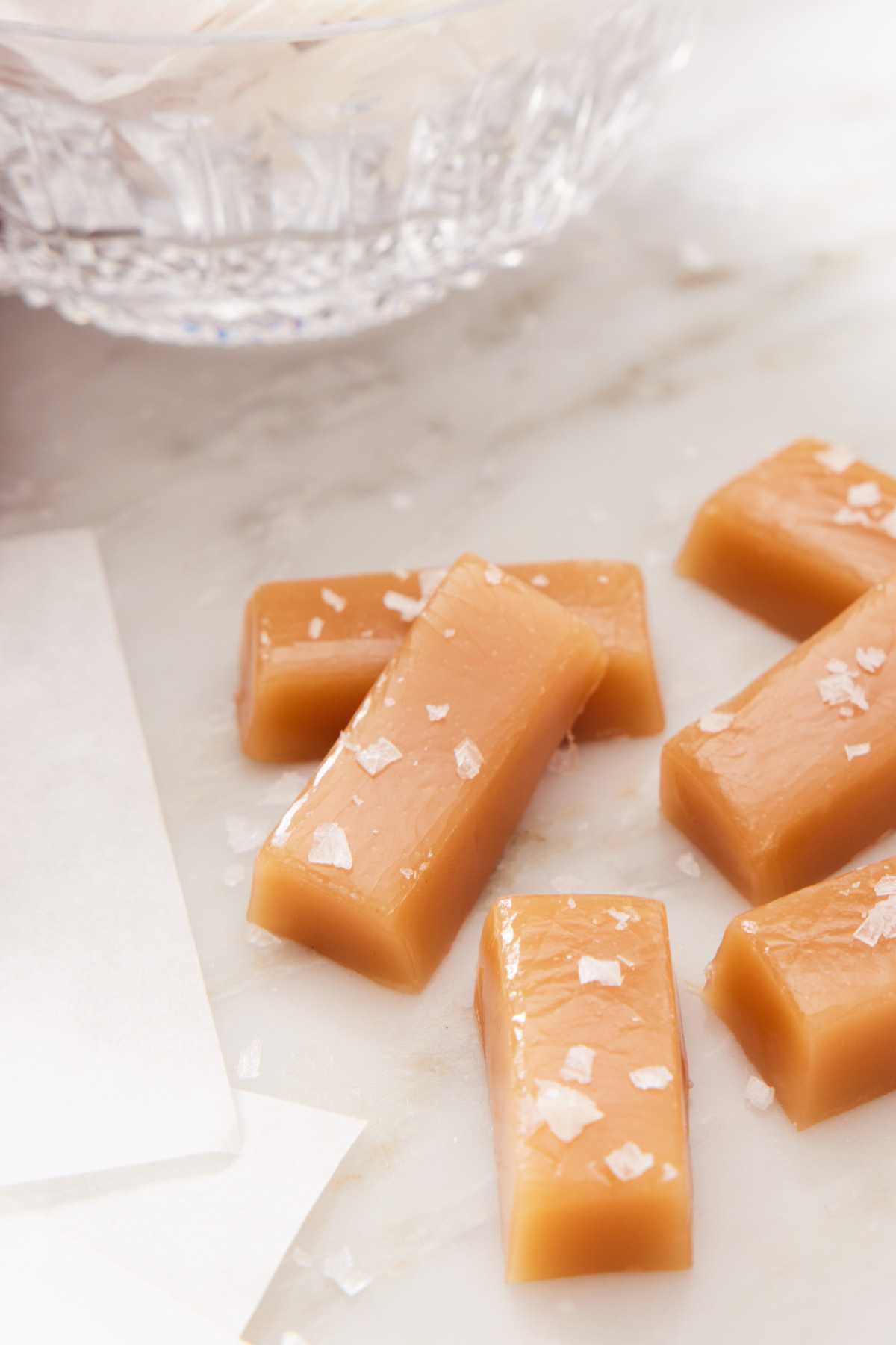 Close up of a few homemade caramel candies sprinkled with flaky sea salt.