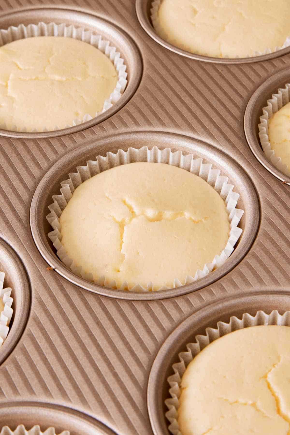 Close-up of mini cheesecakes with an overwhipped filling, to show how they puff up and crack.