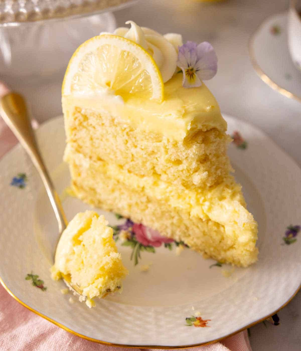 A slice of layered lemon cake with some scooped out with a fork.