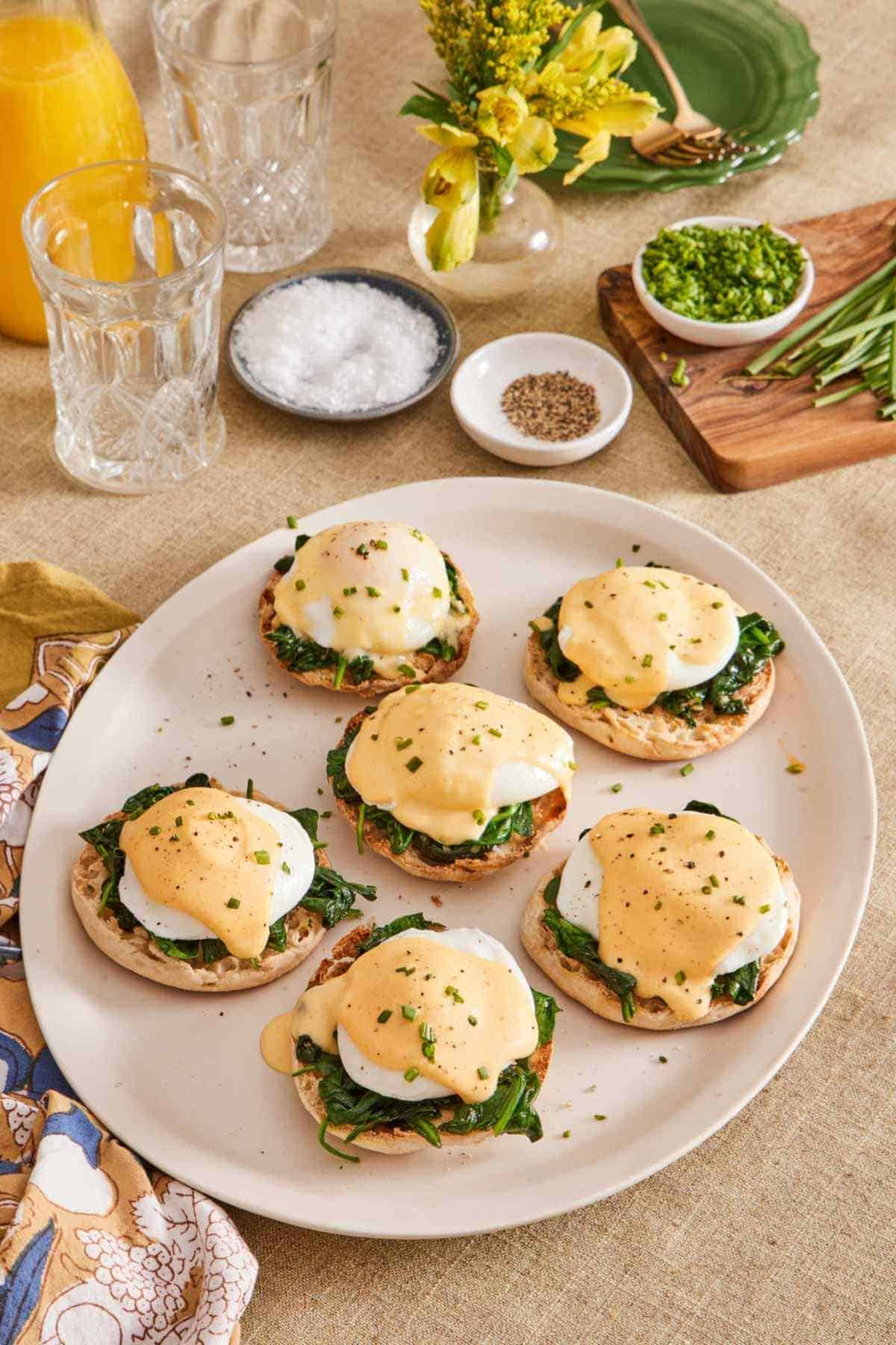 Numerous eggs Florentine on a platter with seasonings in the background.