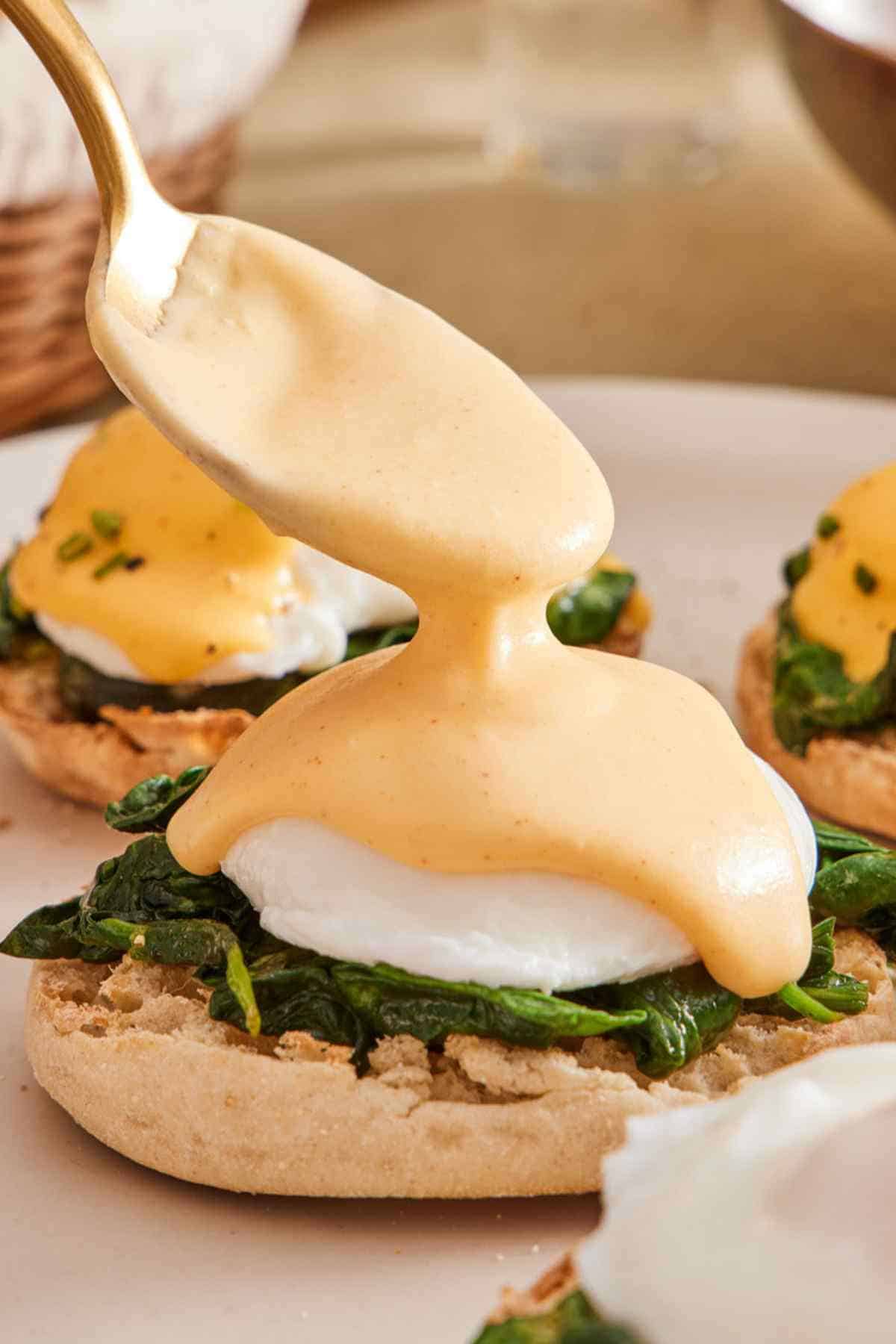 Egg Florentine with hollandaise sauce being spooned over the top.