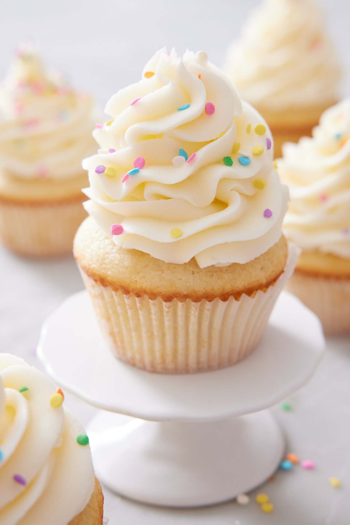 A frosted vanilla cupcake with sprinkles.