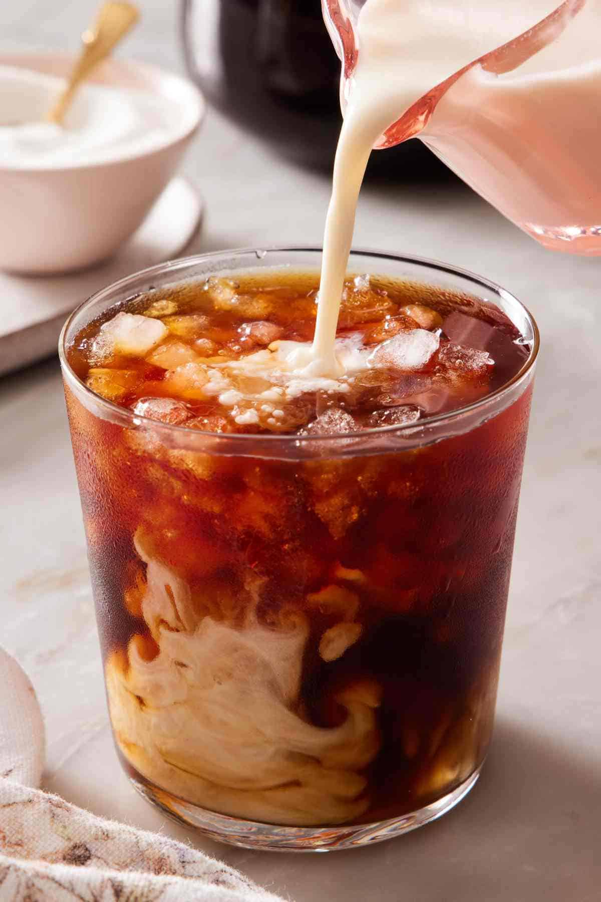 Milk poured into a glass of homemade cold brew.