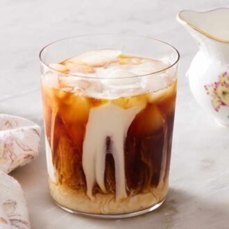 A glass of cold brew coffee with milk poured in but not stirred.