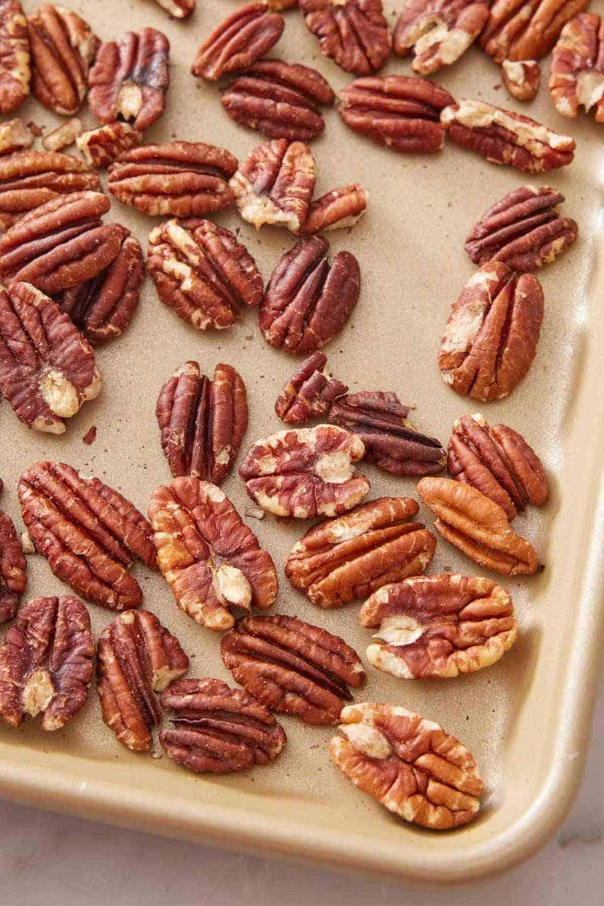 Close-up of a portion of a sheet pan with toasted pecans.