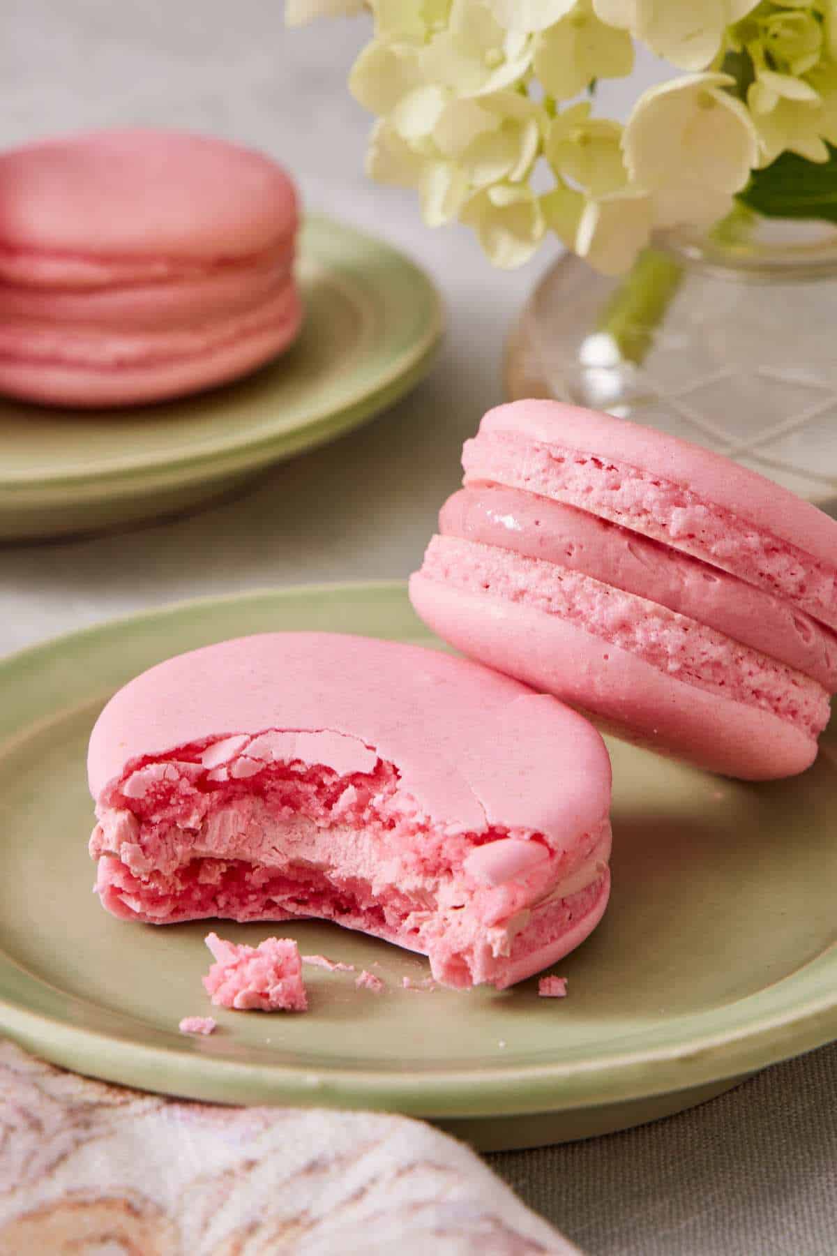 Two French macarons on a small plate, a bite taken out of one