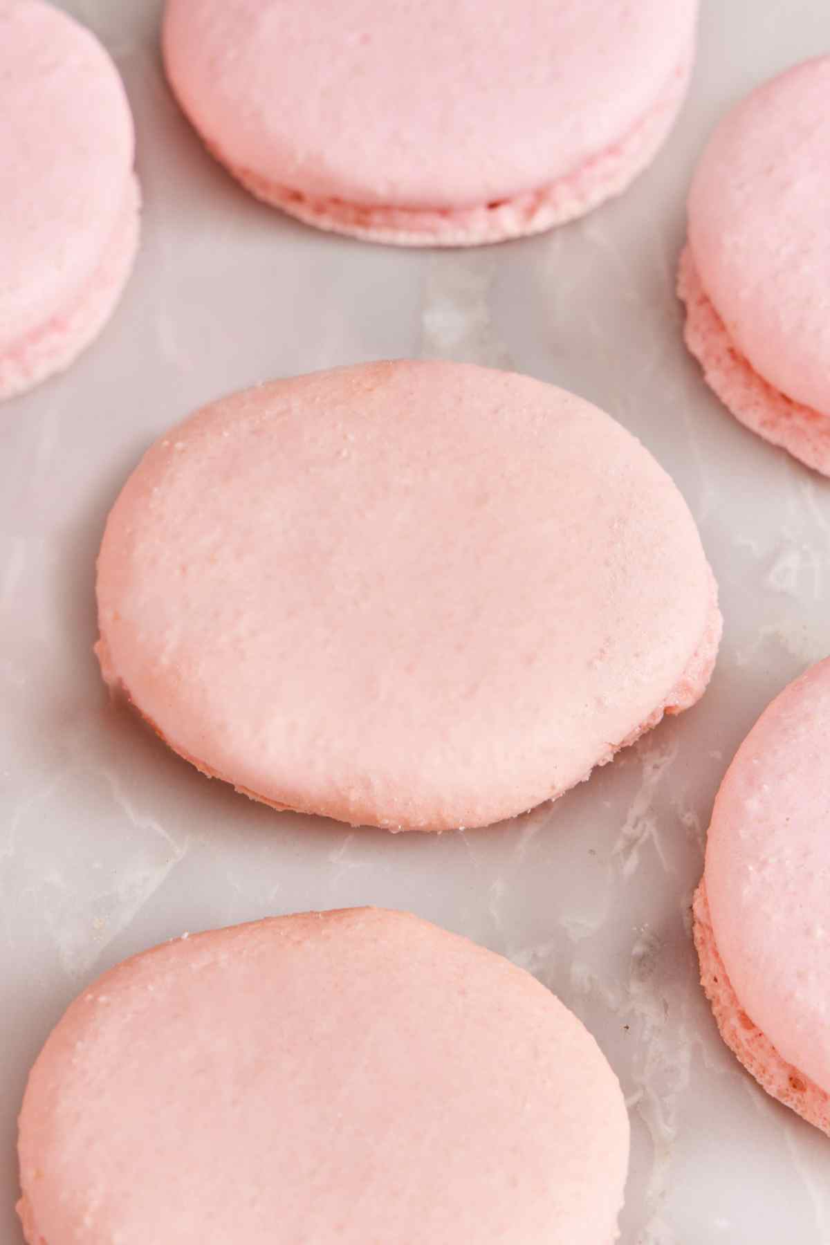 Close-up of a few baked macaron shells made with overmixed batter.