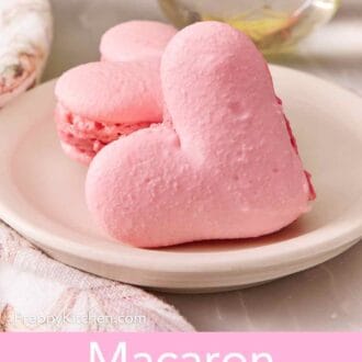 Pinterest graphic showing two heart-shaped macarons on a plate, one leaning against the other.