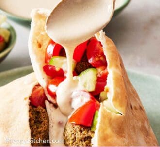 Pinterest graphic showing tahini sauce drizzled with a spoon over a falafel-filled pita pocket.