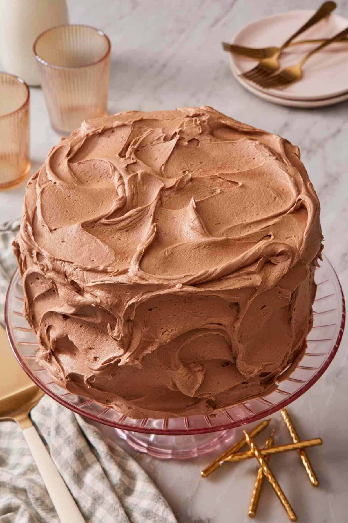 Yellow cake frosted with swoops of chocolate buttercream on a cake stand.