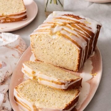 Lemon poppy seed loaf on a platter with a few slices cut out.