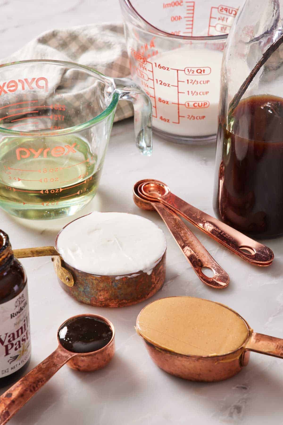Different wet ingredients like milk and peanut butter on measuring cups and spoons.