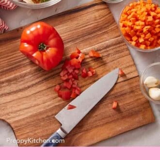 Pinterest graphic showing a tomato, partially chopped, on a wooden cutting board with a knife. More chopped veggies around it, as well as a trash bowl.